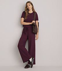 A young woman in a burgundy loungewear set and brown loafers stands against a plain white background, carrying a quilted brown tote bag. carousel Product Image 1