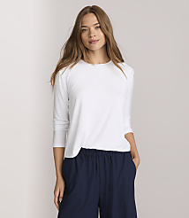 A woman in a white long-sleeved shirt and navy pants stands against a plain white background. carousel Product Image 2