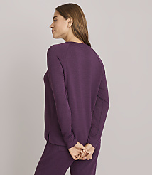 A woman in a purple sweatshirt and pants stands with her hands clasped behind her back against a plain gray background. carousel Product Image 3