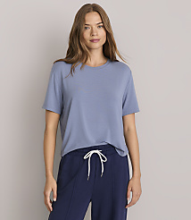 A woman in a blue t-shirt and navy pants stands against a plain gray background. carousel Product Image 1