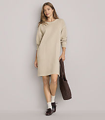 A woman in a beige dress and loafers stands against a plain gray background, holding a brown tote bag. carousel Product Image 1