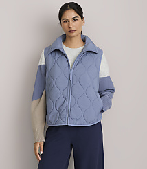 A woman in a blue quilted vest and a color-blocked sweater stands against a plain background. carousel Product Image 1