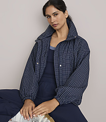 A woman in a navy checkered jacket and matching pants sits against a plain, light gray background. carousel Product Image 2