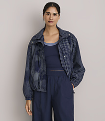 A woman in a blue checkered jacket and navy blue athletic wear stands against a plain gray background. carousel Product Image 1