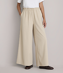 A person stands in wide-leg beige pants and brown shoes against a plain gray background. carousel Product Image 2
