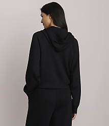 A woman in a black hoodie and pants stands with her back to the camera against a plain gray background. carousel Product Image 3