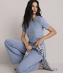 A woman in a blue t-shirt and wide-leg pants poses against a plain gray background, with a plaid shirt tied around her waist. carousel Product Image 2