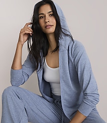 A woman in a blue hoodie and matching pants poses against a plain, light-colored background.