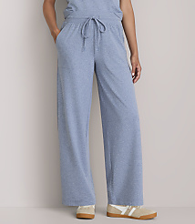 A person stands in light blue wide-leg lounge pants and sneakers against a plain gray background. carousel Product Image 2