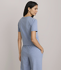 A woman in a blue t-shirt and pants stands with her hands in her pockets against a plain gray background. carousel Product Image 3