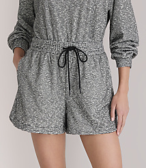 A person models a grey and white patterned romper with a black drawstring in the foreground, against a plain white background. carousel Product Image 2