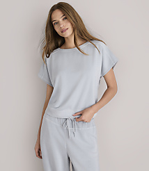 A woman in a light gray loungewear set stands against a plain white background.