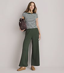 A woman in a striped shirt and wide-leg green pants stands against a plain white background, holding a brown bag. carousel Product Image 2