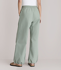 A person wearing loose-fitting, light green pants with elastic cuffs stands with their back to the camera against a plain white background. carousel Product Image 3