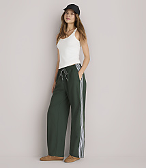 A woman in a white tank top and green track pants stands against a plain white background. carousel Product Image 1