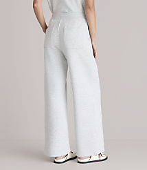 A person wearing light gray wide-leg sweatpants and white sandals stands against a plain white background. carousel Product Image 3