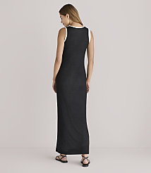 A woman in a black maxi dress with a white trim stands facing away from the camera against a plain, light-colored background. carousel Product Image 3