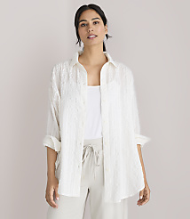 A woman in a white textured shirt and light-colored pants stands against a plain white background. carousel Product Image 1