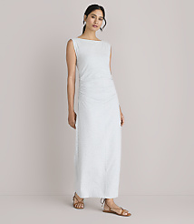 A woman in a light-colored, ruched maxi dress stands against a plain white background. carousel Product Image 1