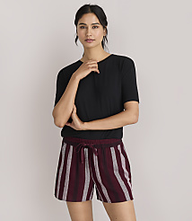 A woman in a black t-shirt and striped shorts stands against a plain white background. carousel Product Image 1