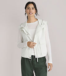 A woman in a light-colored hooded vest and white shirt looks to the side against a plain white background. carousel Product Image 1
