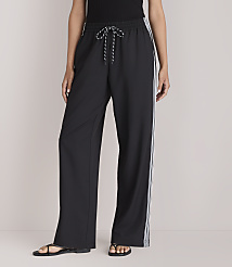 A person stands in black wide-leg pants with white stripes down the sides, against a plain white background. carousel Product Image 2