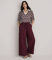 A woman in a burgundy and white chevron-patterned knit polo shirt and burgundy pants stands against a plain white background. carousel Product Image 2