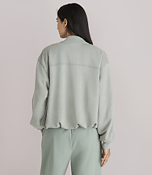 A woman in a light green sweatshirt and pants stands against a plain white background. carousel Product Image 3
