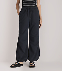 A person stands in black balloon pants and sandals against a plain white background. carousel Product Image 2