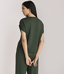 A woman in a dark green top and pants stands with her back to the viewer against a plain white background. carousel Product Image 3