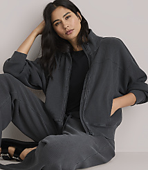 A woman in a dark grey zip-up jacket and matching pants stands against a plain white background. carousel Product Image 2