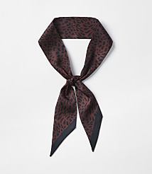 A brown leopard-print silk scarf with a black border is tied in a knot against a plain white background. carousel Product Image 1