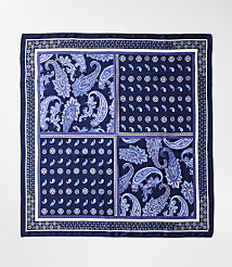 A square silk scarf with a dark blue border features four distinct quadrants of paisley and floral patterns in shades of blue and white, set against a plain white background. carousel Product Image 2