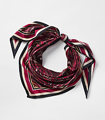 A maroon silk scarf with a paisley pattern and striped border is tied in a knot against a plain white background. carousel Product Image 1