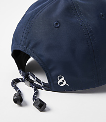 A close-up of a navy blue baseball cap with an adjustable drawstring in the foreground is set against a plain white background. carousel Product Image 2