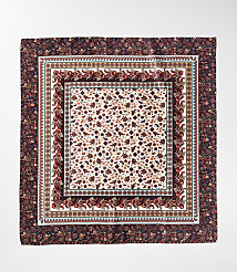 A square silk scarf with intricate paisley and floral patterns in shades of burgundy and cream is laid flat against a white background. carousel Product Image 2