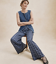 A woman in a denim vest and patterned pants sits on a stool against a plain, light-colored background. carousel Product Image 4