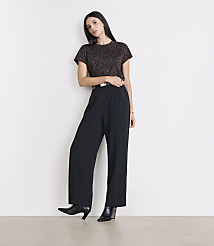A woman in a leopard print top and black wide-leg pants stands against a plain white background. carousel Product Image 1