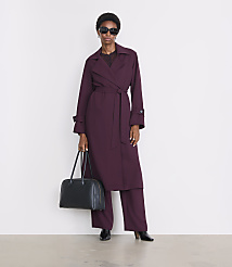 A woman in a plum trench coat and matching pants stands with a dark handbag against a plain white background. carousel Product Image 1