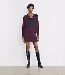 A woman in a burgundy cardigan, black top, and matching skirt stands in front of a plain white background. carousel Product Image 1