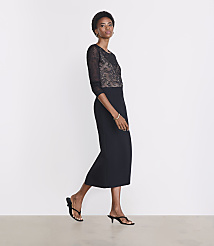 A woman in a black lace-bodice dress and heeled sandals stands against a plain white background. carousel Product Image 1