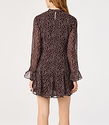 A woman in a dark, polka-dotted dress with flared sleeves stands against a plain white background. carousel Product Image 2