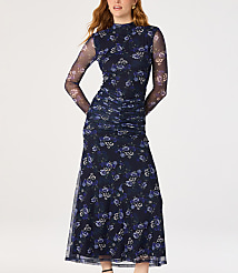 A woman in a dark floral mesh dress stands against a plain white background. carousel Product Image 1