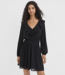 A woman in a black ruffled dress stands against a plain white background. carousel Product Image 2