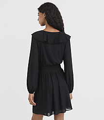 A woman in a black ruffled dress stands against a plain white background. carousel Product Image 3