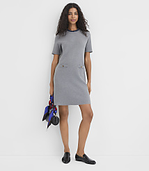 A woman in a grey dress and black loafers stands against a plain white background, holding a patterned scarf and a small black purse. carousel Product Image 1