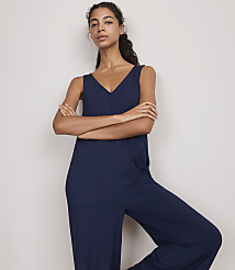 A woman in a navy blue jumpsuit stands with her arms crossed against a plain, light-colored background. carousel Product Image 2