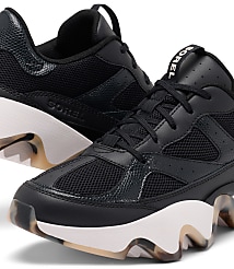 A pair of black Sorel sneakers with white soles and a marbled pattern on the heel and sole are in the foreground, with a blurred background. carousel Product Image 6