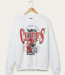 A white Kansas City Chiefs sweatshirt with a graphic of a helmet and team name hangs on a wooden hanger against a plain white background. carousel Product Image 1