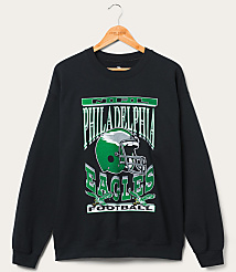 A black Philadelphia Eagles sweatshirt with a graphic of a helmet and eagles hangs on a wooden hanger against a plain white background. carousel Product Image 1